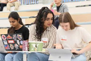 Three international students sit in a lecture while working on their computers at San José State University.