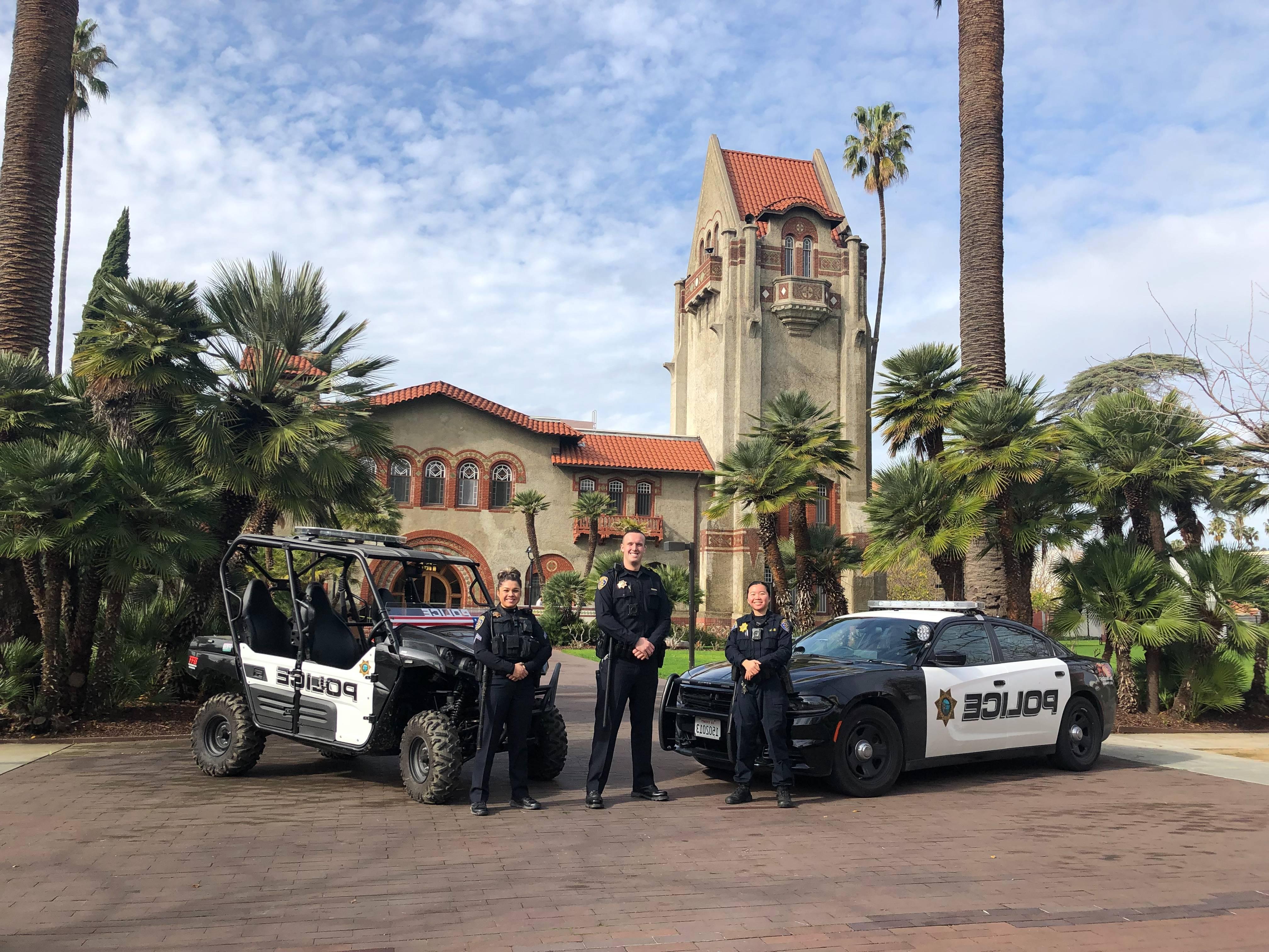 Male university police officer stands by his car smiling